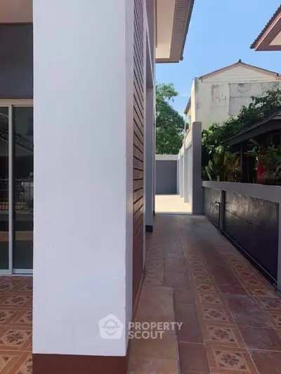 Modern exterior view of a residential property with tiled walkway and garden area.