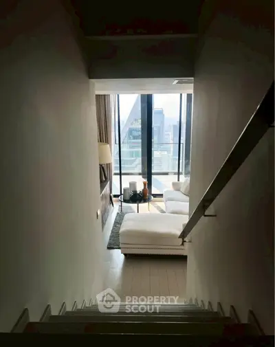 Modern living room with large windows and city view, featuring a cozy white sofa and stylish decor.