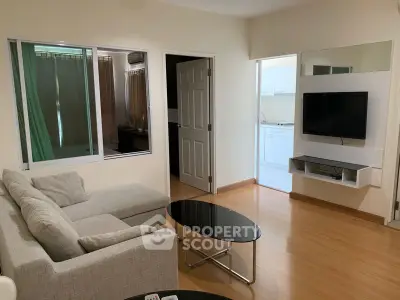 Modern living room with sleek furniture and wall-mounted TV, leading to a bright kitchen area.