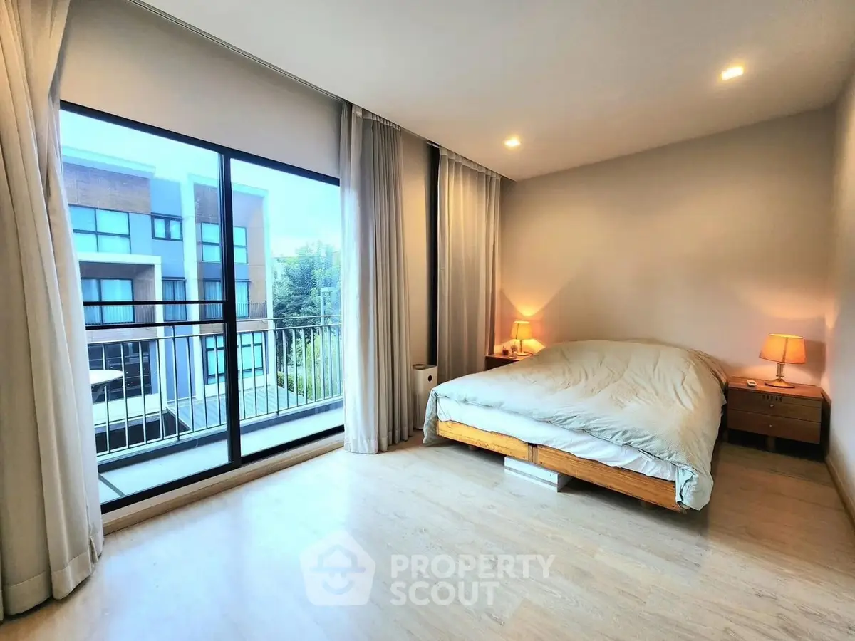 Spacious bedroom with large window and balcony view in modern apartment.