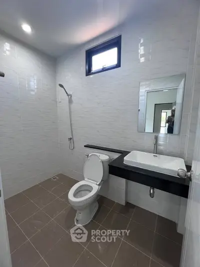 Modern bathroom with sleek fixtures and neutral tiles, featuring a shower and large mirror.