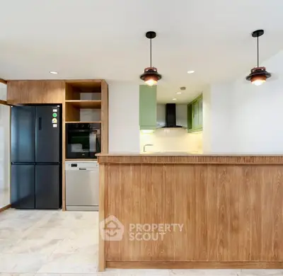 Modern kitchen with wooden cabinetry, black fridge, and stylish pendant lights.