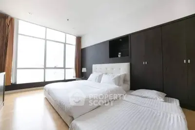 Spacious bedroom with large windows and modern furnishings in a luxury apartment.