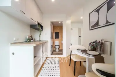 Modern studio apartment with compact kitchen and dining area, featuring stylish decor and wooden flooring.