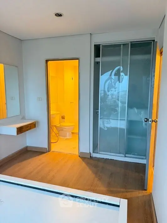 Modern bathroom with wooden flooring and glass shower enclosure