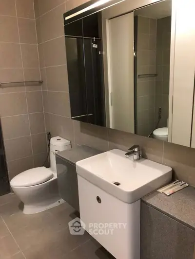 Modern bathroom with sleek fixtures and large mirror in contemporary apartment.