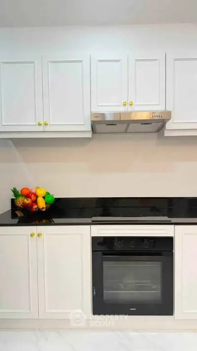 Modern kitchen with sleek white cabinets and built-in oven, perfect for culinary enthusiasts.