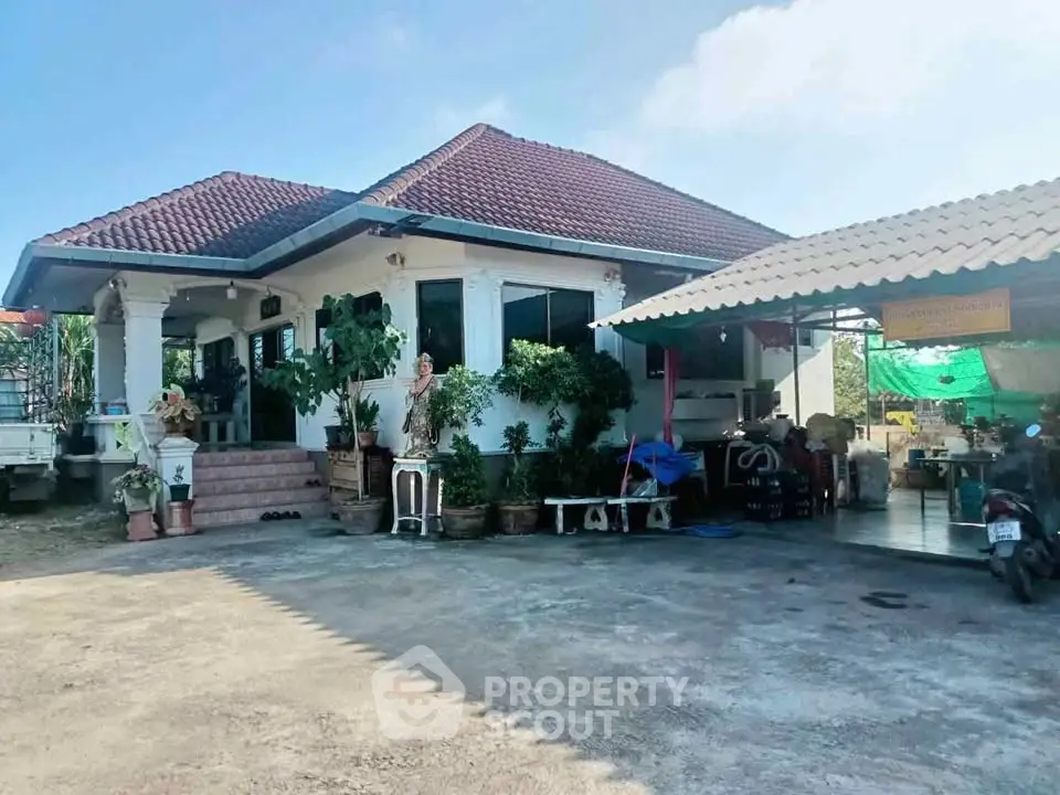 Charming single-story house with red-tiled roof and lush garden, perfect for serene living.