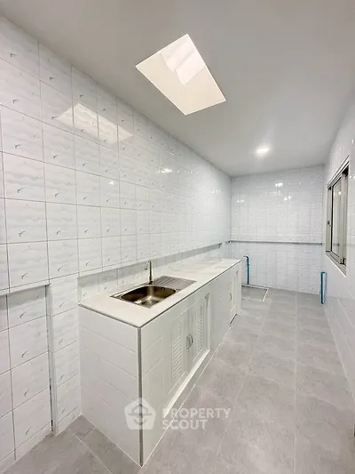 Spacious modern kitchen with sleek white tiles and ample counter space