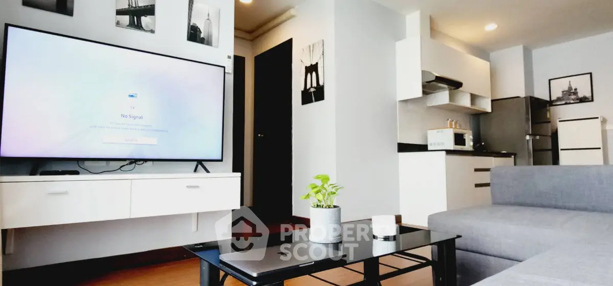 Modern living room with sleek furniture and large TV in a stylish apartment.
