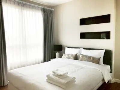 Cozy bedroom with elegant decor and natural light, featuring a neatly made bed and stylish curtains.