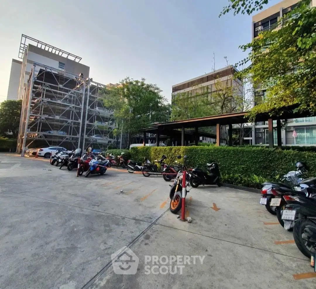 Modern building exterior with parking area and lush greenery, ideal for urban living.