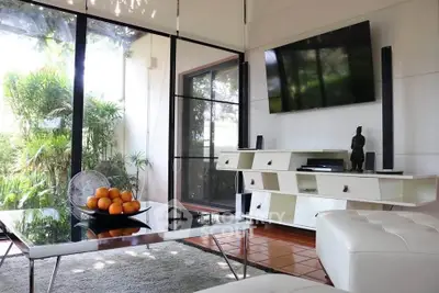 Stylish living room with modern furniture and large windows overlooking lush greenery.