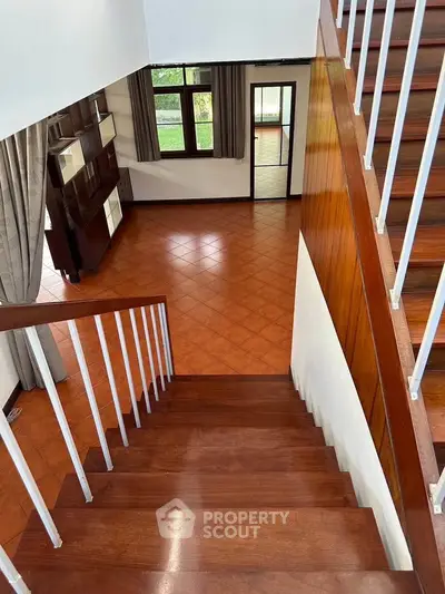 Spacious two-story home with elegant wooden staircase and large windows for natural light.
