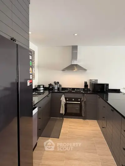 Modern kitchen with sleek black countertops, stainless steel appliances, and open layout design.