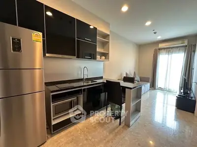 Modern kitchen with sleek black cabinets and stainless steel appliances in a stylish apartment.