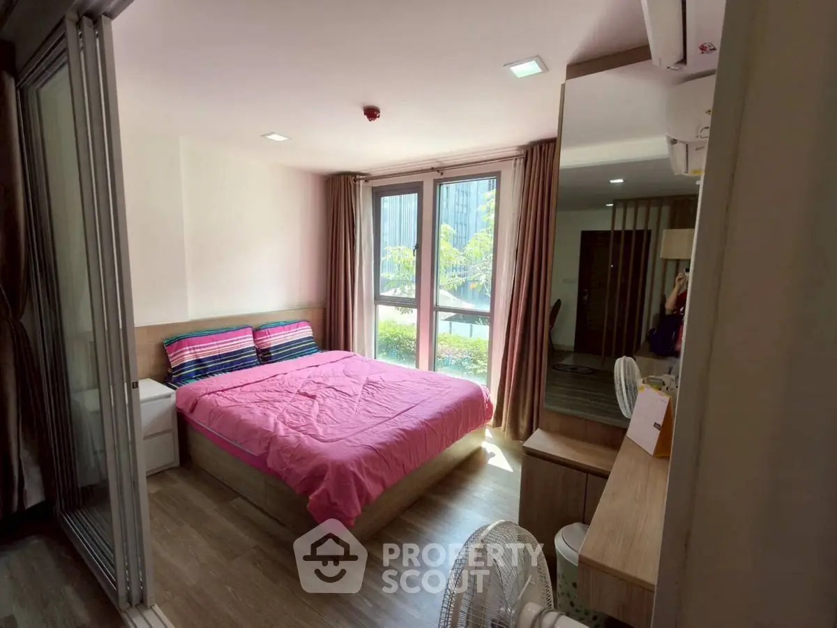 Cozy bedroom with large windows and pink bedding in modern apartment