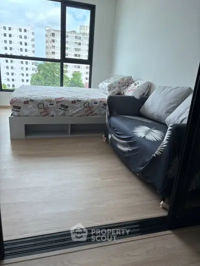 Modern bedroom with cozy sofa and large window offering city view