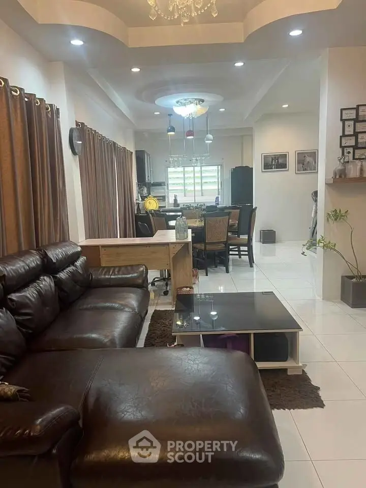Spacious living room with elegant leather sofa and modern open kitchen layout, perfect for family gatherings.