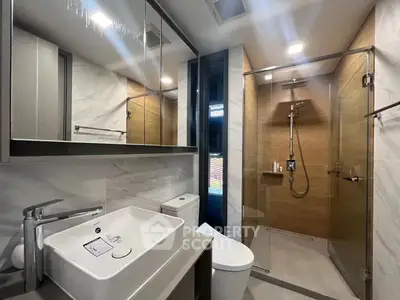 Modern bathroom with glass shower and sleek fixtures in contemporary apartment.