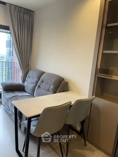 Modern living room with cozy sofa and dining area in a high-rise apartment with city view.