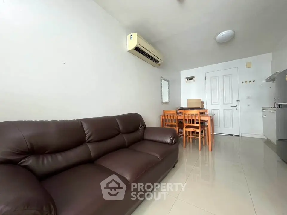 Modern living room with leather sofa and dining area in a bright apartment.
