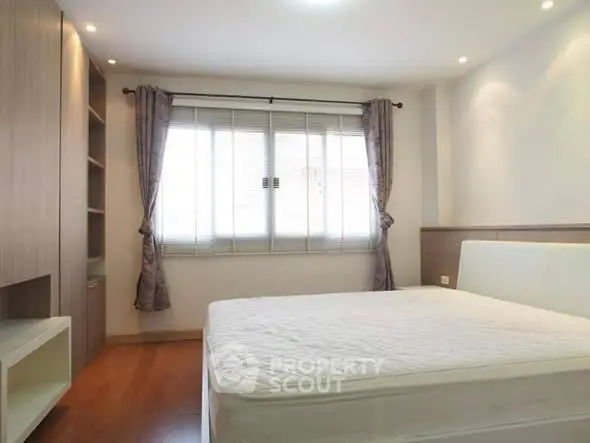 Spacious and bright bedroom with modern furnishings and large window.