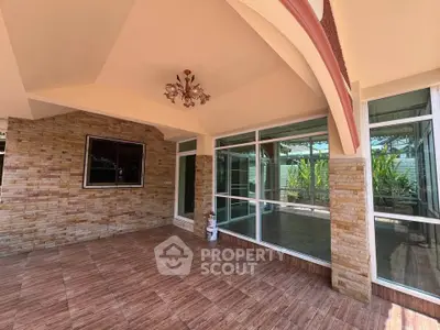 Spacious covered patio with elegant stone wall and large glass doors.
