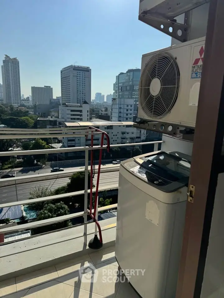 City view balcony with air conditioning unit and washing machine, perfect for urban living.