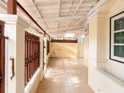 Spacious covered outdoor area with tiled flooring and decorative railing, perfect for relaxation or entertaining.