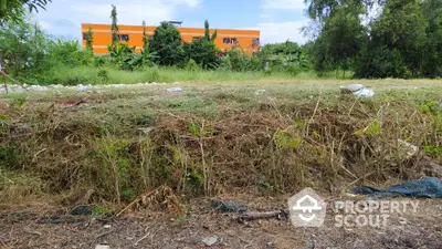 Vacant land with potential for development, surrounded by greenery and a distant building view.