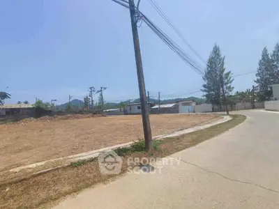 Expansive vacant land ready for development, located at a serene crossroad with clear skies and potential for various projects.