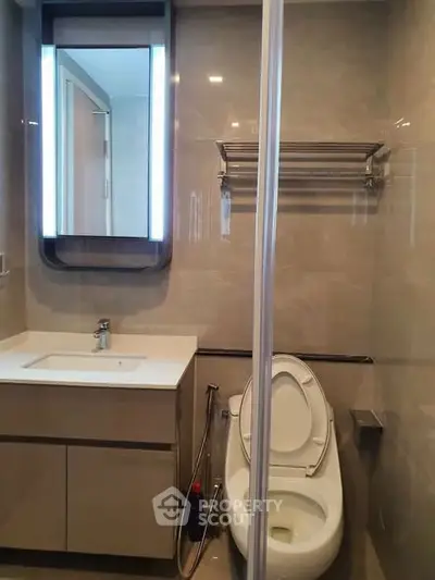 Modern bathroom with sleek fixtures and illuminated mirror in a contemporary apartment.
