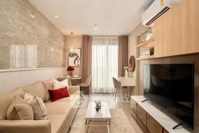 Modern living room with elegant decor, large TV, and natural light from window.
