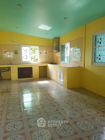 Spacious kitchen with vibrant yellow walls and patterned tile flooring, featuring ample natural light.