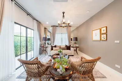Elegant living room with wicker chairs, plush sofa, and large windows offering garden views.