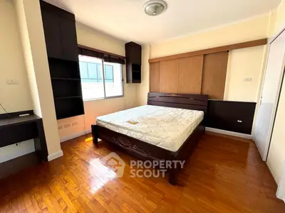 Spacious bedroom with wooden flooring and large window for natural light.