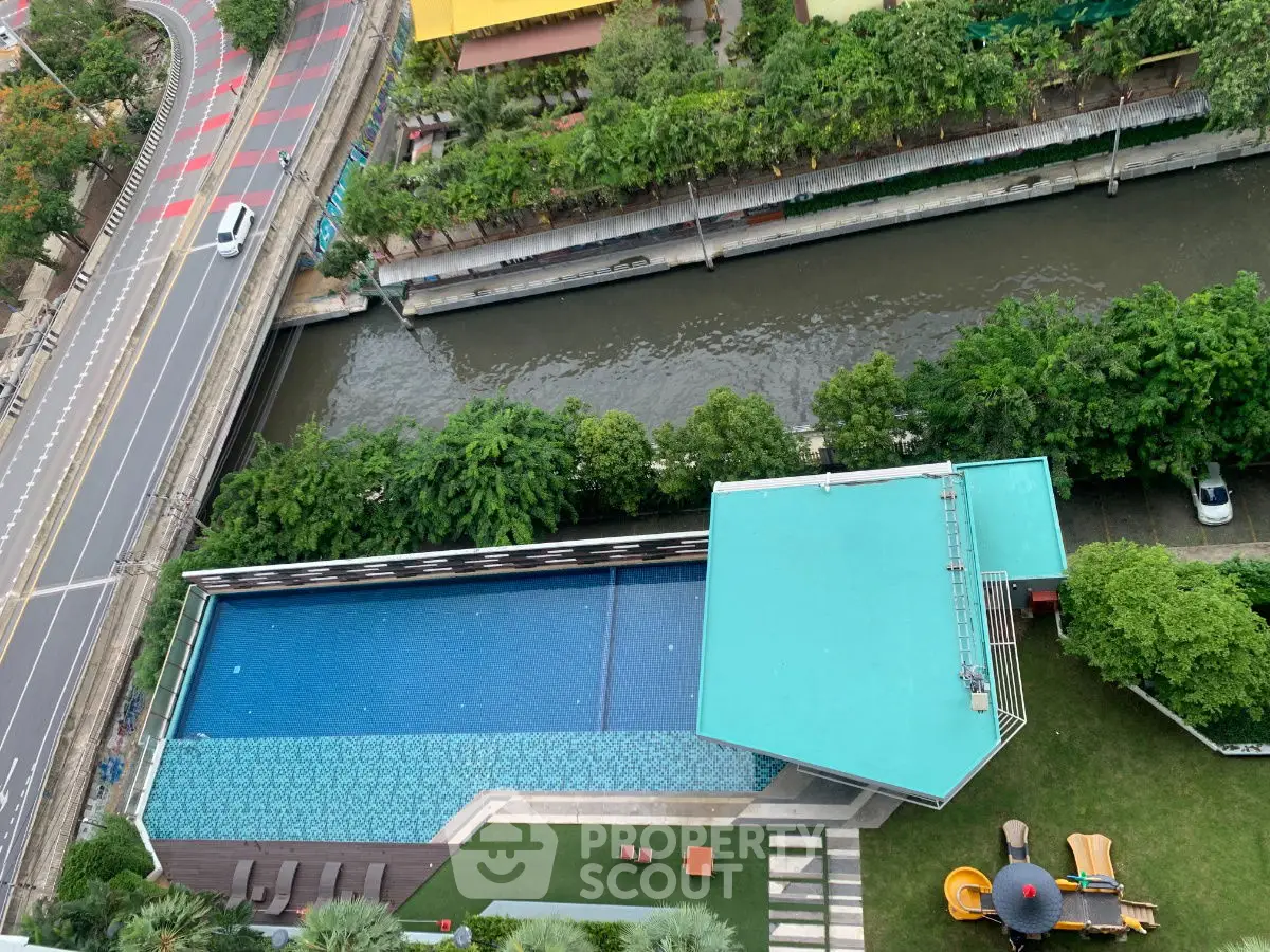 Stunning aerial view of modern poolside area with lush greenery and canal backdrop.