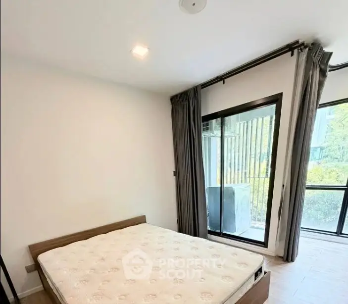 Spacious bedroom with large windows and garden view, featuring a comfortable bed and modern decor.
