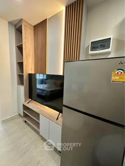 Modern apartment interior with sleek TV setup and stainless steel fridge