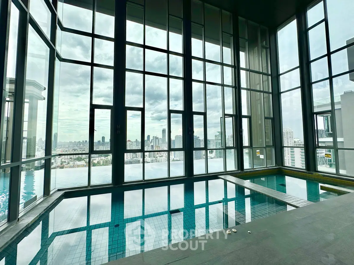 Luxurious indoor pool with stunning city skyline view through floor-to-ceiling windows.