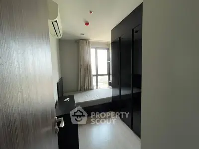 Modern bedroom with large window and sleek black wardrobe in a high-rise apartment.