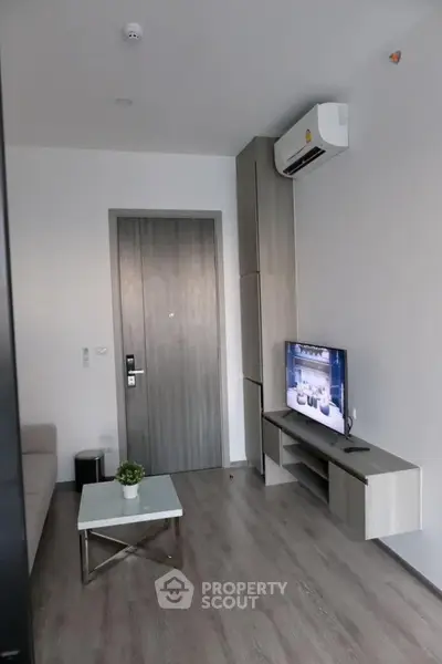 Modern living room with sleek furniture and wall-mounted TV in a stylish apartment.