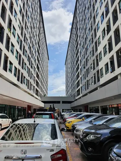 Modern apartment complex with parking area and clear blue sky view.