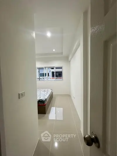 Bright and minimalist bedroom with tiled flooring and large window.