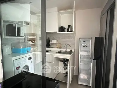 Compact modern kitchen with appliances including washing machine and fridge in sleek apartment.