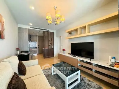 Modern living room with stylish decor and open kitchen layout, featuring a cozy sofa and large TV.