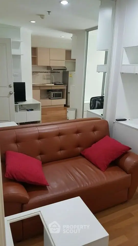 Cozy living room with leather sofa and modern kitchen in open layout apartment.