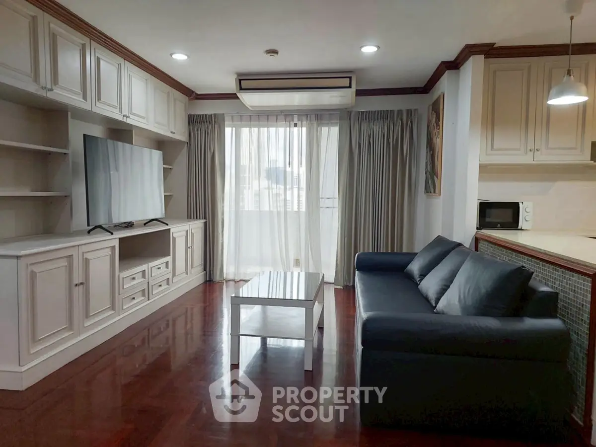 Spacious living room with modern furnishings and large TV in a stylish apartment.