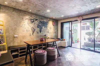 Stylish modern dining area with a world map wall decor, sleek flooring, and access to a cozy outdoor space, perfect for urban living.